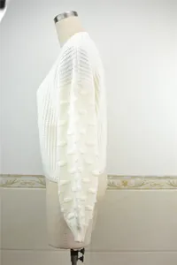 Side profile of a white chunky knit sweater with decorative puff sleeves on a mannequin