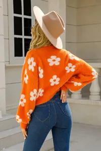 Vista trasera de un suéter de punto naranja con flores y sombrero fedora beige