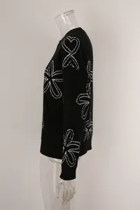 Detailed side profile of a black long-sleeved crewneck sweater with white floral patterns