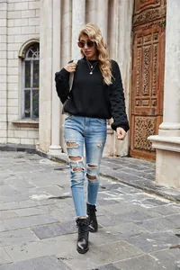 Full body view of model wearing a black bubble sleeve knitted sweater in a street setting