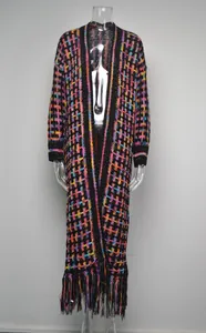 Detailed view of a long knit cardigan featuring a colorful grid pattern and fringe hem.