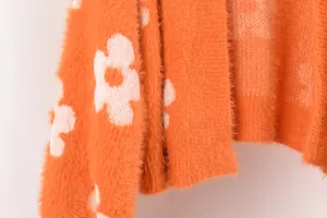 Primer plano de tela de punto naranja suave con un detalle de patrón floral blanco