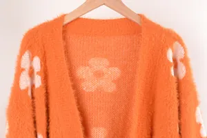Vista detallada de cárdigan naranja de punto peludo con diseño de flores blancas