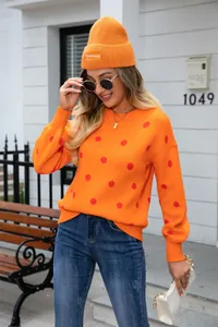 Close-up of vibrant orange polka dot crewneck sweater with cozy knit texture
