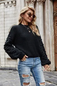 Detailed view of women's black knit sweater with decorative bobble sleeves