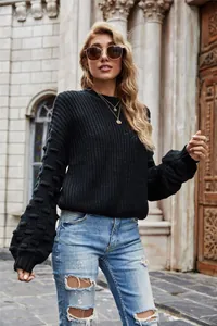 Close-up detail of a black chunky knit sweater featuring stylish textured bubble sleeves.