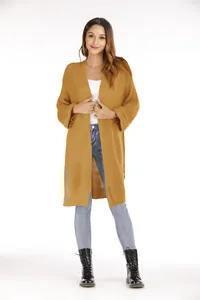 Model trägt eine senfgelbe lange Strickjacke und Jeans vor weißem Hintergrund