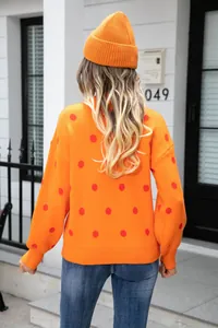 Detailed back view of an orange oversized pullover sweater with red polka dots.