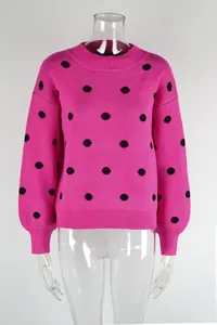 Close-up detail of pink knit sweater with black polka dots and ribbed cuffs