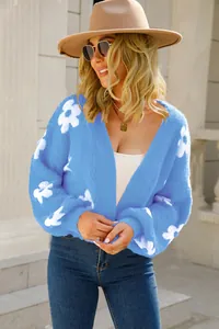Mujer de moda con un cárdigan de punto azul con motivos de flores blancas al aire libre