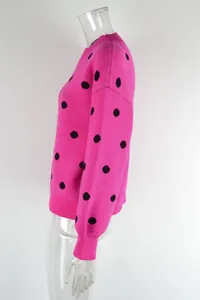 Close-up detail of hot pink knit sweater featuring black polka dots and ribbed texture