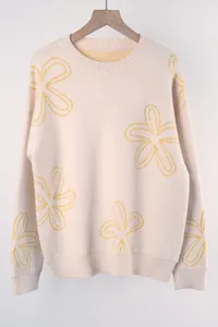 Detail view of light beige knit sweater with yellow floral pattern and ribbed cuffs