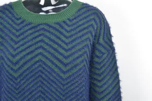Close-up of fuzzy navy and green chevron knit texture on a crew neck women's sweater.