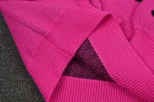 Detail view of pink knit sweater hem showcasing fine ribbed texture and black polka dots