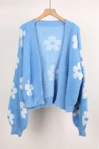 Detalle de una chaqueta de punto azul suave con motivos florales blancos y textura.