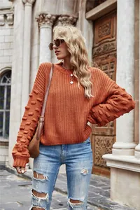 Outdoor fashion shot of orange textured knit pullover sweater with unique bobble sleeves