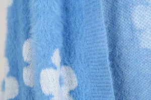 Vista macro que muestra la textura suave y el patrón de flores blancas de un cárdigan azul