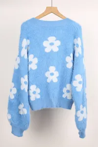 Detalle de un suéter azul claro peludo con estampado floral blanco en una percha
