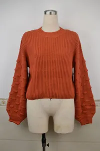 Detail view of orange knit sweater with popcorn stitch lantern sleeves on mannequin