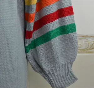 Gros plan sur la manche lanterne à rayures colorées et le poignet côtelé du pull gris.