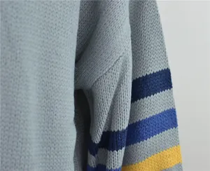 Gros plan de la maille épaisse d'un pull bleu clair avec détail de manches rayées