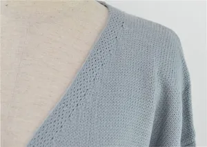 Détail d'un gilet en tricot bleu clair montrant la texture fine et l'encolure.