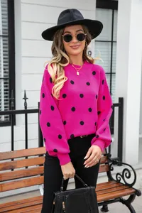 Full view of a woman wearing a vibrant pink polka dot knitted pullover sweater outdoors