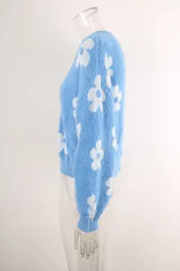 Detalle de vista lateral de un suave suéter de punto azul con flores blancas grandes