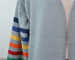 Détail d'un cardigan en maille bleu clair avec des rayures arc-en-ciel vives sur la manche