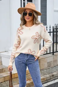 Elegant woman wearing a beige floral knit sweater paired with blue jeans and a tan fedora hat.