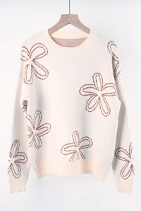 Front view of off-white knitted sweater with brown flower outlines on wooden hanger