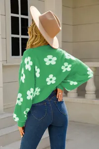 Vista trasera de un suéter de punto verde con patrones florales blancos en modelo.