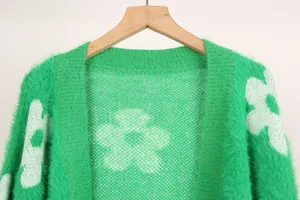 Primer plano de cárdigan de punto verde suave con diseño de flores blancas