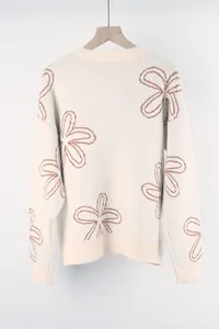 Close-up of cream knitted sweater featuring brown floral outline patterns