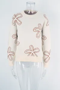 Detailed view of cream knit sweater featuring elegant brown flower outlines and soft ribbed texture