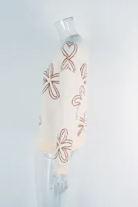 Side detail view of cream plus size knitted sweater featuring brown floral line art patterns