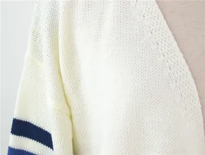Vue macro de la texture d'un pull en maille blanc avec des rayures bleu marine aux manches