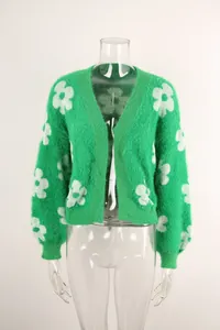Detalle de cárdigan de punto verde con motivos florales blancos y textura suave y esponjosa