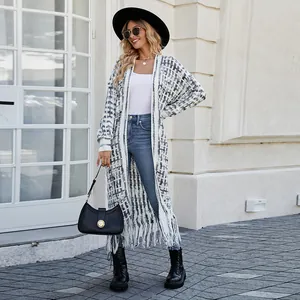 Stylish woman in a long checkered cardigan with fringe hem and black wide-brim hat.