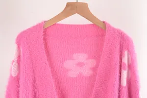 Primer plano de un cárdigan de punto rosa suave con diseño de flores blancas