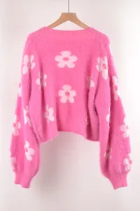 Primer plano detallado de un suave jersey de punto rosa con grandes flores blancas