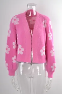 Detalle de la texture del cárdigan rosa peludo con grandes motivos florales blancos.