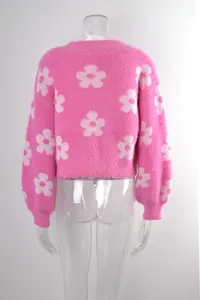 Vista posterior de un cárdigan corto rosa peludo con motivos de flores blancas en maniquí