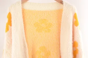 Primer plano de la textura del cárdigan de punto suave con diseño floral amarillo.