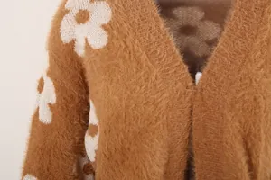 Primer plano de un cárdigan de punto peludo marrón con patrones florales blancos.