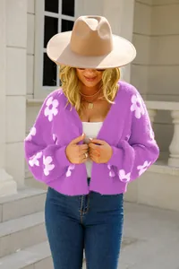 Detalle de un cárdigan de punto morado suave con motivos de flores blancas en una modelo.