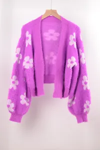 Detalle de cárdigan de punto morado suave con flores blancas en percha