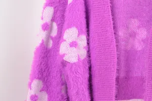 Vista detallada de la suave textura peluda y el patrón de flores blancas de un cárdigan morado