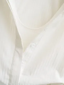 Detailed macro shot of white vertical striped shirt bodysuit featuring button detail