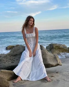 Elegante vestido largo blanco de verano con detalles de volantes en un entorno de playa.